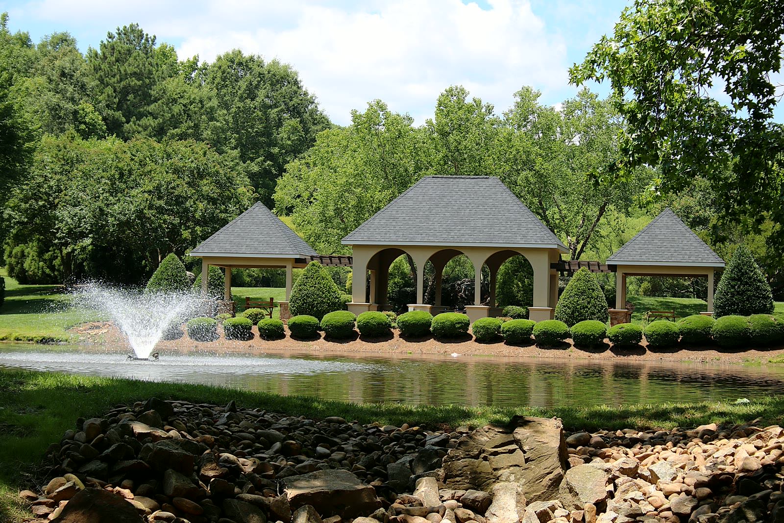 The community pavilion and pond fountain framed by manicured gardens