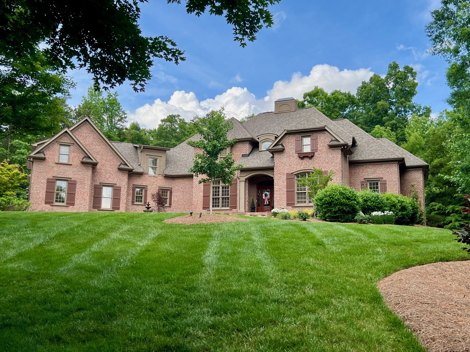 Red brick French country home nestled among the trees