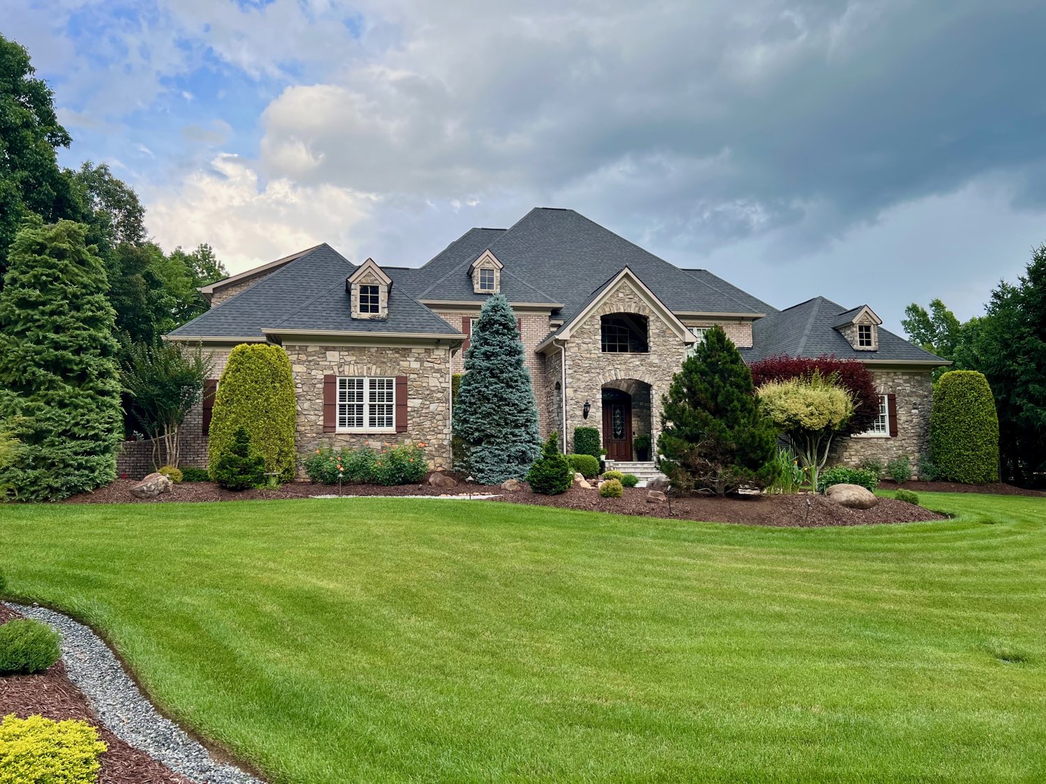 Stone French country home beneath a dramatic sky