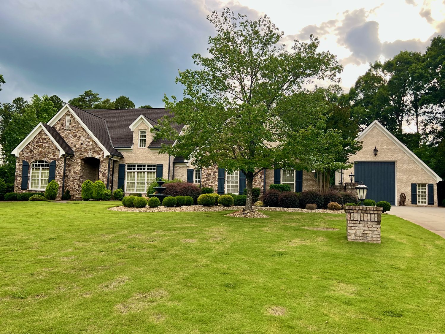 Brick and stone French country home with a manicured lawn